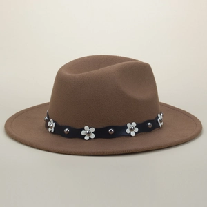 Detail of brown wool fedora hat featuring black band with white petals and silver rivets