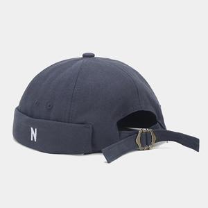 Detail of adjustable metal buckle and N embroidery on navy cotton docker cap