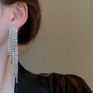 Gros plan de boucles d'oreilles pompons argentées avec strass portées par un mannequin
