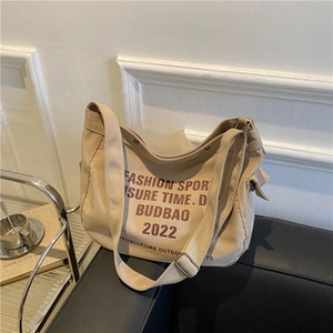 Dettaglio della borsa a secchiello in tela beige con scritte fashion sport stampate