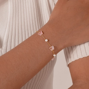 Detail of children's gold chain bracelet with pink butterfly charms and white pearls