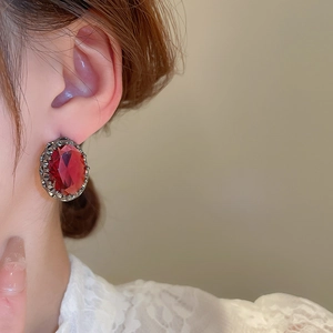 Close-up of vintage oval red gemstone stud earrings worn by a model in a side profile