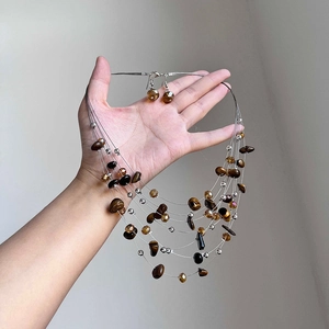 Close-up of beaded necklace and earrings set with tiger eye stones and clear crystal beads