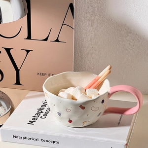Detail of ceramic mug with irregular wave rim and ergonomic pink shaped handle