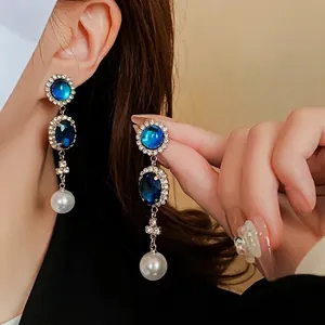 Blue crystal and pearl drop earrings on model with elegant vintage silver plating