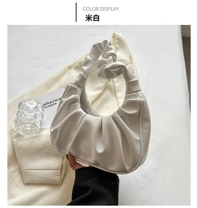Detail of a creamy white pleated cloud bag showing the soft faux leather texture