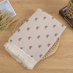 Detail of double-layer cotton baby blanket featuring brown rainbows and fringe tassels