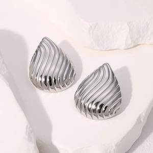 Boucles d'oreilles gouttes argentées texturées présentées sur un support en pierre