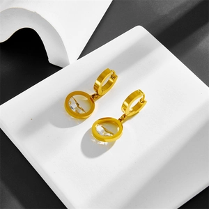 Modern gold hollow frame earrings with round black shell pendant on a stone block