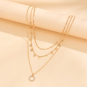Detail of gold multilayered necklace with sequins and a sparkling rhinestone ring pendant