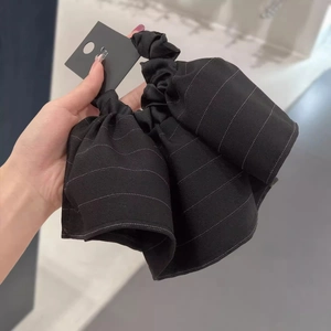 Close-up of black striped fabric hair scrunchie with layered ruffles and textured bow