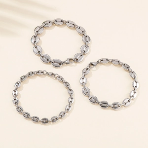 Three silver coffee bean link bracelets with lobster clasps on light beige background