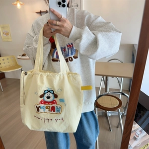 Detail of cute dog embroidery and drawstring closure on the yellow canvas tote bag