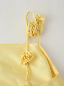Détail de la robe en satin jaune avec fleur 3D et boucle métallique sur la bretelle