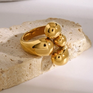 Polierter goldener Edelstahlring mit Kugeln auf beigem Travertin-Stein-Podest