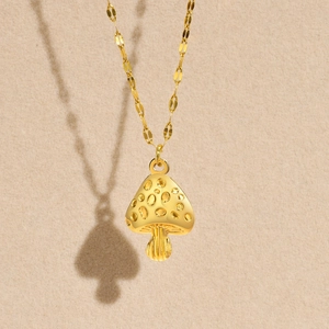 Close-up of golden mushroom pendant necklace with a polished finish and fine chain detail