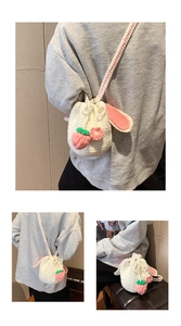 Detail of handmade crochet bucket bag with pink rabbit ears and strawberry charms