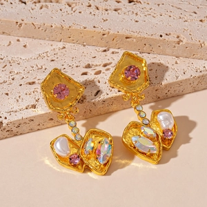Close-up of vintage gold earrings with pink zircon, pearls, and colorful crystals