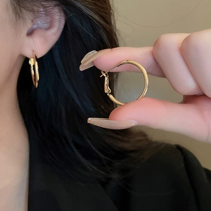 Close-up of gold geometric hoop earrings with polished finish and hinged closure