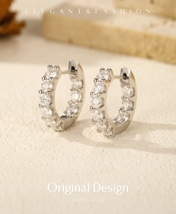 Dettaglio di orecchini a cerchio in argento 925 con moissanite su sfondo materico