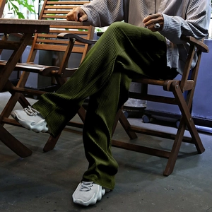 Detail of olive green pleated wide-leg pants showing texture and draped fabric finish