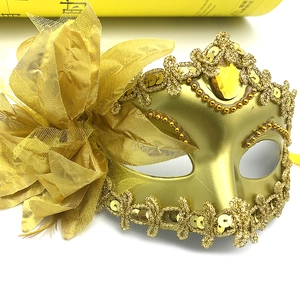Detail of a gold masquerade mask featuring a side flower and sparkling sequin trim