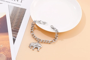 Close-up of silver steel chain bracelet featuring a detailed elephant charm on a dish