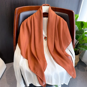 Detailed texture of lightweight orange cotton linen scarf draped over a wooden chair