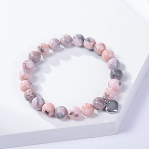 8mm pink zebra stone beaded bracelet with silver heart pendant on a white platform