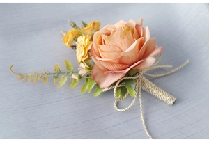 Close-up of champagne silk rose boutonniere pinned on a grey suit with golden stem detail