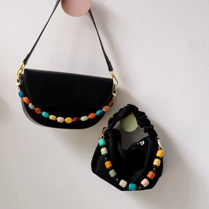 Detailed shot of vibrant resin bead chain attached to stylish black shoulder handbag