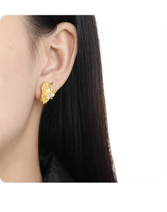 Close-up of asymmetrical gold studs with irregular bark texture and sparkling diamond inlay