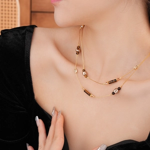 Detail einer geschichteten Goldkette mit braunen Tigerauge-Perlen an einem Modell