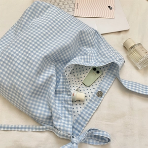 Detail of blue gingham canvas tote bag showing magnetic buckle and polka dot lining