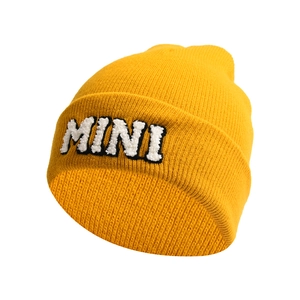 Detail of yellow knit beanie featuring a white fuzzy MINI letter patch embroidery