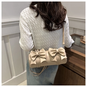 Detail of beige cylinder bag featuring soft PU leather and large decorative bow ties