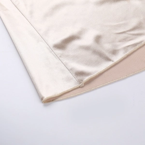 Gros plan détaillé de la robe en satin champagne montrant le tissu brillant et la couture