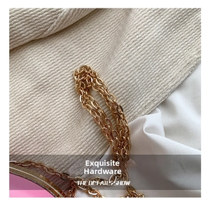 Close-up of golden interlocking chain strap on a pink leather heart bag detail