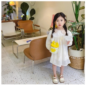 Detail of a white dress paired with a yellow heart pattern bucket bag for young girls