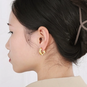 Detail of 18K gold C-shaped earrings with embedded white pearls on professional model