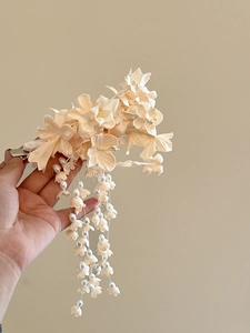 Close-up of Lily of the Valley hair clip with fabric petals and pearl tassel details