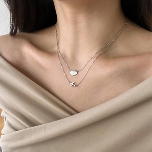 Detail of S925 sterling silver layered necklace with plane and cloud pendants on model
