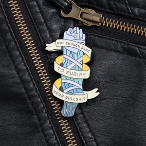 Macro shot of an enamel sage bundle brooch with humor text on a black leather jacket