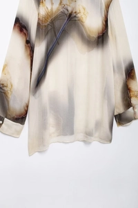 Dettaglio della stampa artistica e della trama in raso sulla camicia beige donna