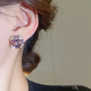 Detailed close-up of square purple crystal stud earrings with diamond halo and gold plating