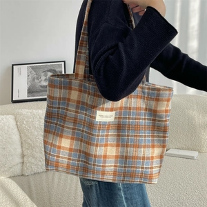 Macro view of vintage plaid tote bag texture with brand label and canvas strap details