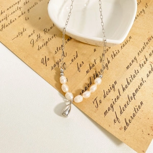 Polished silver teardrop pendant with lustrous pearl chain necklace on vintage paper