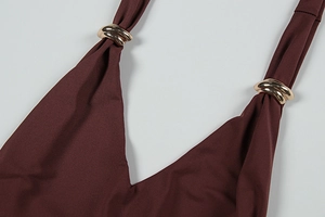 Close-up of golden wavy metal buckles on burgundy V-neck dress straps for women