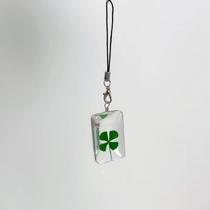 Macro shot of natural four-leaf clover pendant in clear resin with a lobster clasp