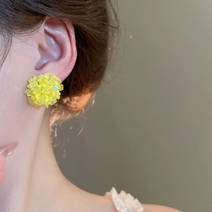 Nahaufnahme einer Frau mit gelben Kristallperlen Ohrsteckern in runder Blumenform